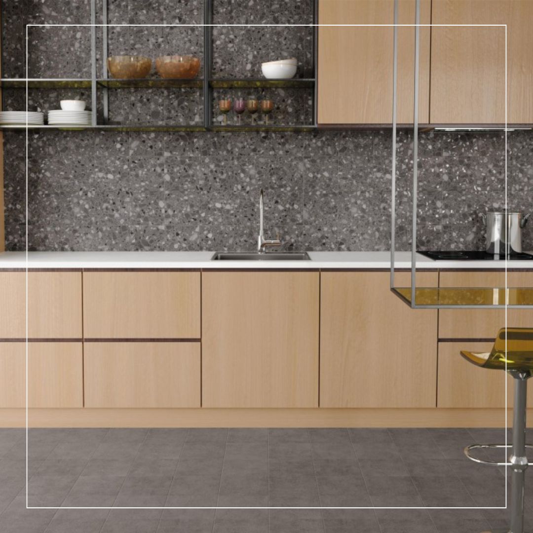 Black and white terrazzo wall tiles used as a modern kitchen backsplash paired with light wood cabinets and a minimalist countertop