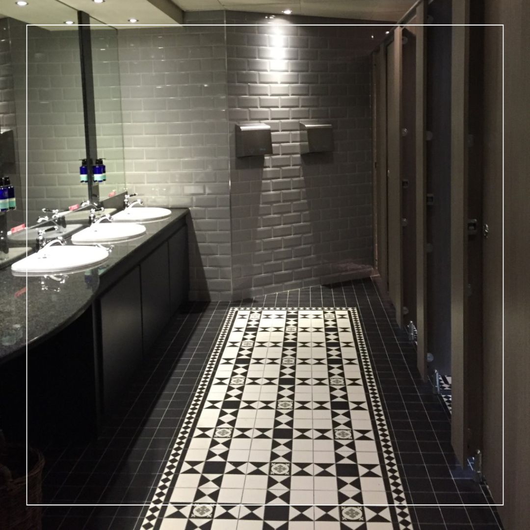 Black and white Victorian floor tiles with geometric pattern used in a modern commercial bathroom interior