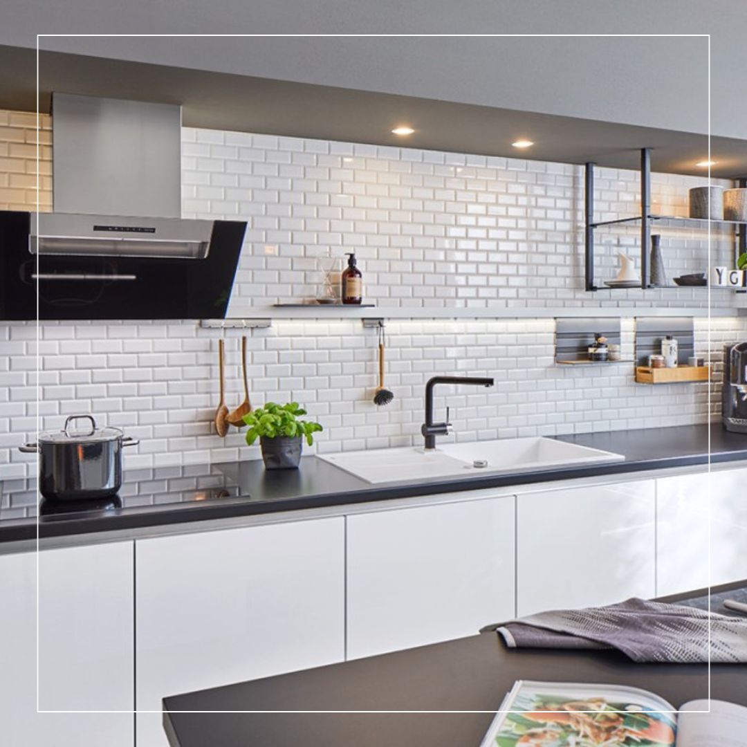 Modern kitchen featuring glossy white ceramic metro tiles used as a stylish kitchen splashback, paired with sleek handleless cabinets and dark worktops for a contemporary finish.