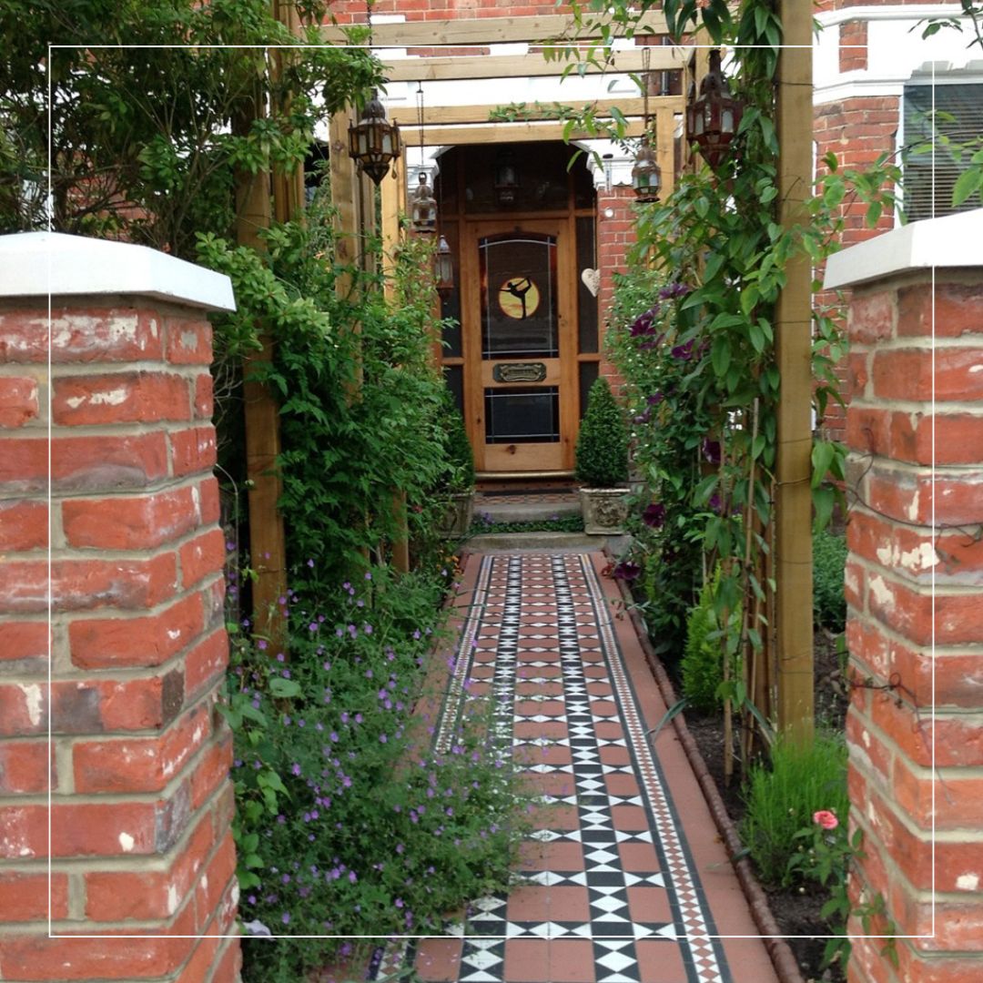 Victorian geometric porcelain pathway tiles with black, white and red pattern leading to a front door entrance.