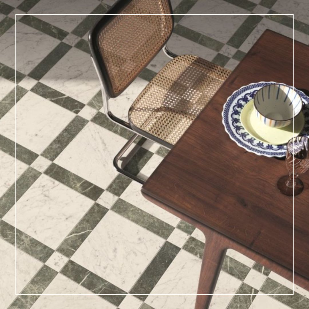dining room with green and white marble effect checkerboard floor tiles, slim verde borders between carrara style squares beneath a wooden table and cane chair