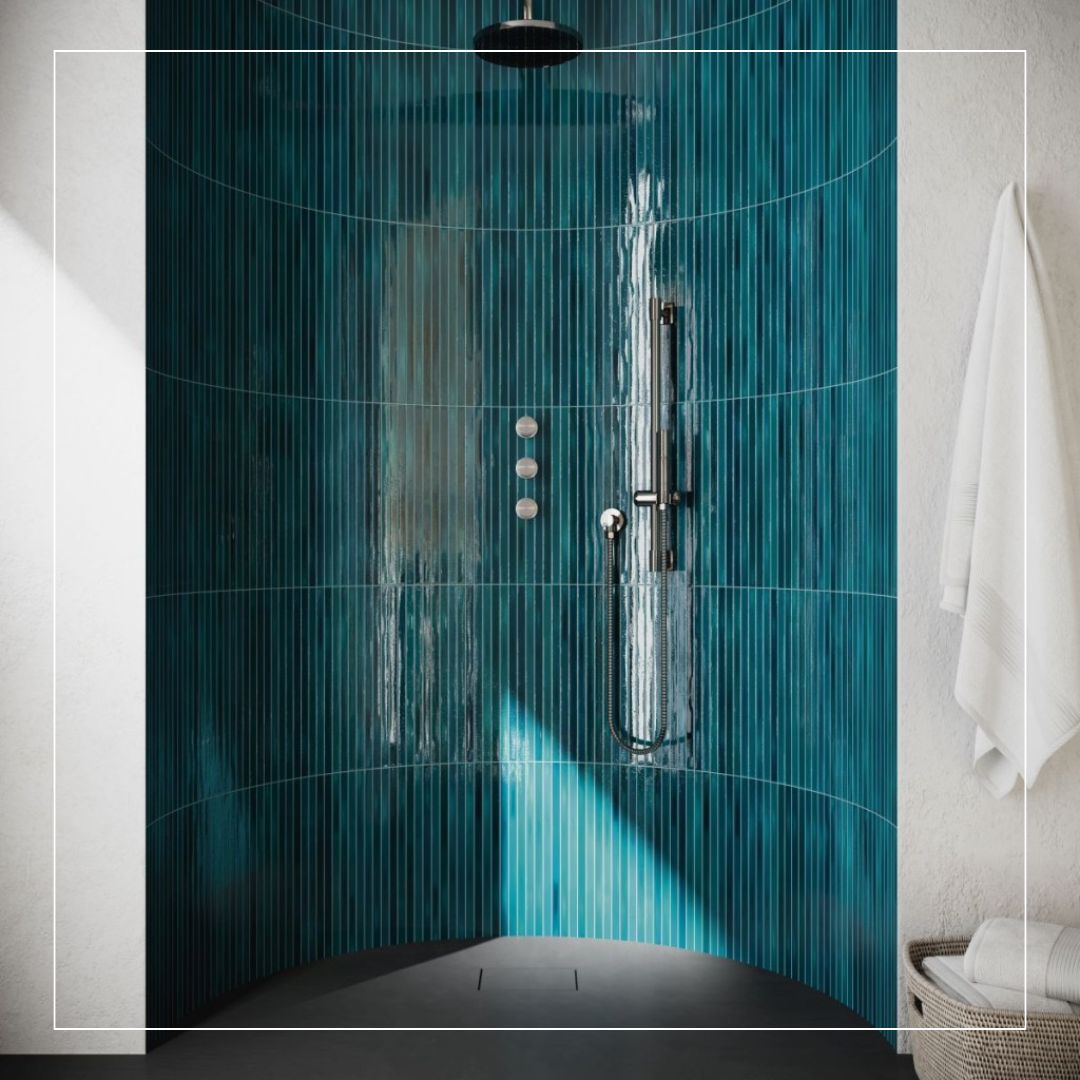 Curved shower wall clad in slim vertical tiles in deep teal and blue tones, creating a striking 60–30–10 colour balance that contrasts with light neutral walls and contemporary chrome fittings