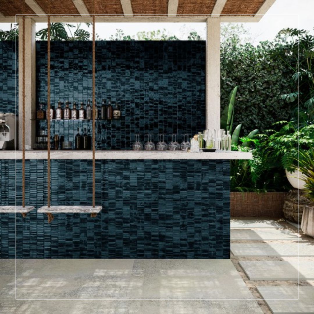 Outdoor bar clad in dark blue and black textured tiles with subtle variation, creating a rich, layered surface that pairs with natural stone, greenery, and warm timber elements
