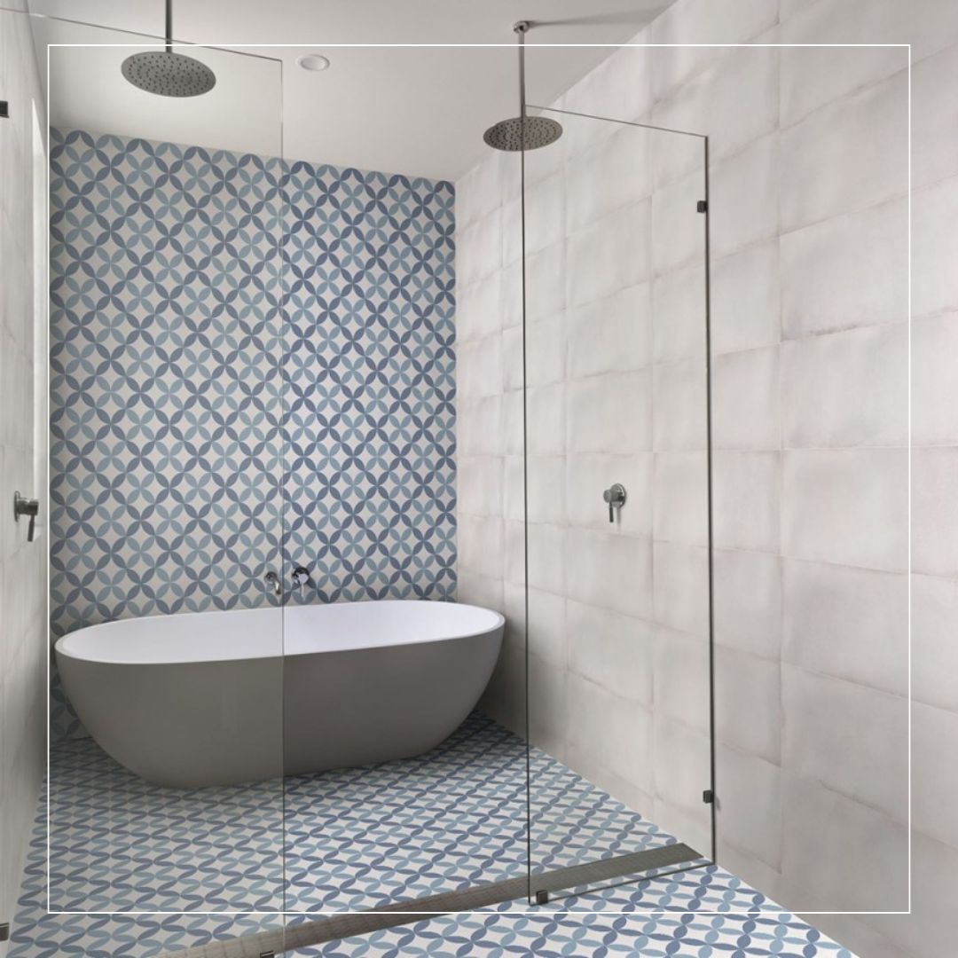 Contemporary bathroom with freestanding bathtub, walk-in glass shower, blue and white patterned floor tiles, and light neutral wall tiles