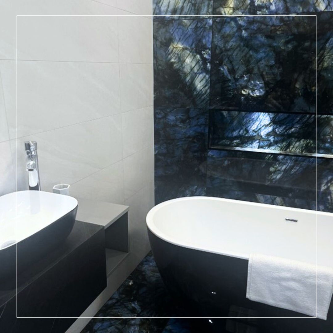 Bathroom interior featuring dramatic dark blue and black marble-effect tiles with natural veining, paired with soft light grey wall tiles