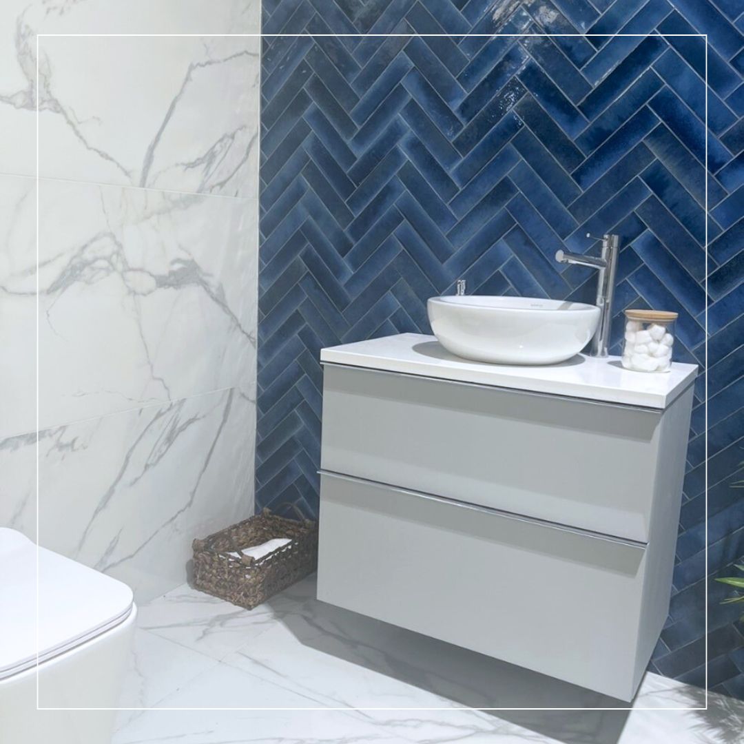Bathroom interior featuring deep blue herringbone wall tiles paired with large-format white marble-effect tiles