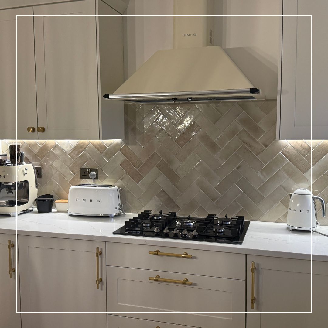 Contemporary kitchen with beige herringbone splashback tiles, white SMEG appliances, and marble worktop