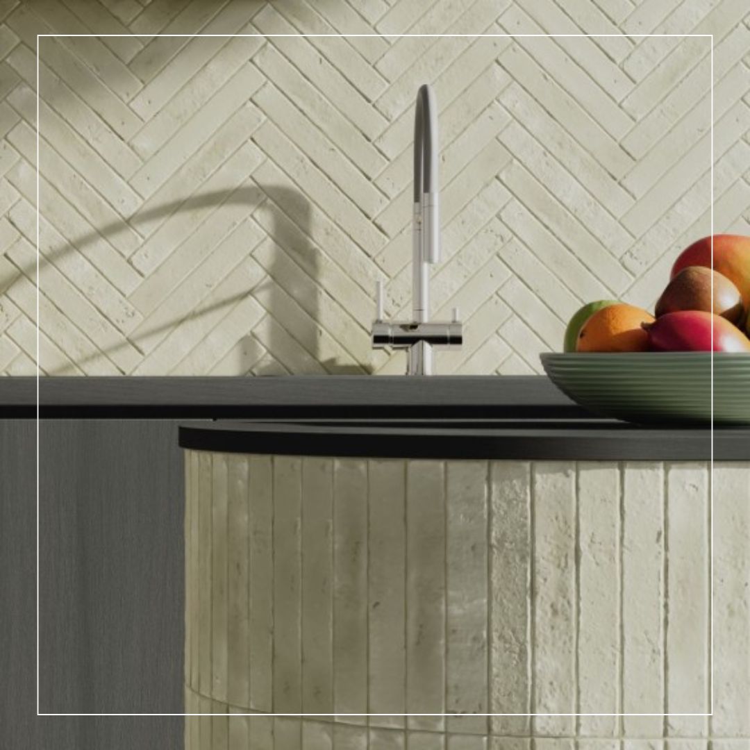Close-up of kitchen sink with cream herringbone splashback tiles and matching textured island design
